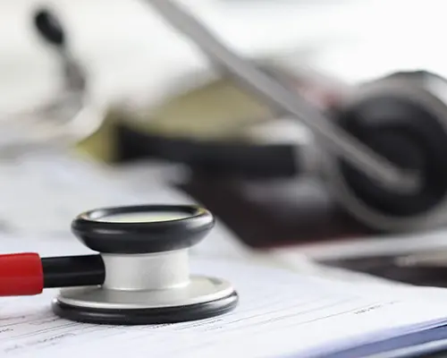 Stethoscope with documents and headphones with microphone on desktop